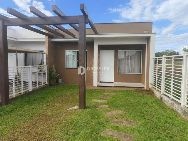 Foto da fachada de uma residência em Lajeado, Brasil, com gramado e estrutura de madeira.