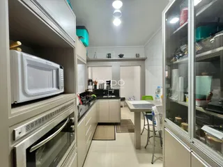 Cozinha com armários brancos e eletrodomésticos em um imóvel.