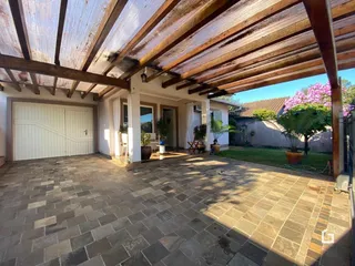 Vista da fachada da casa com garagem e área externa pavimentada.