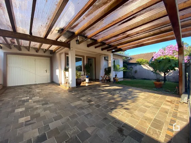 Vista da fachada da casa com garagem e área externa pavimentada.