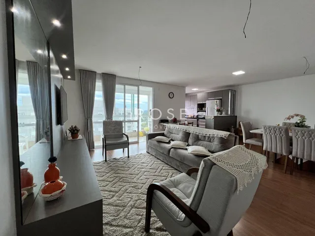Sala de estar ampla com piso de madeira e grandes janelas.