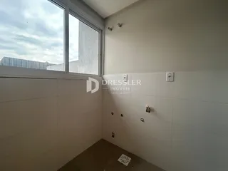 Vista de um canto interno de um cômodo com parede clara e janela.