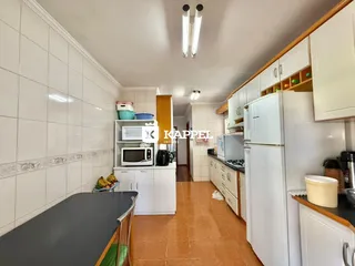 Cozinha com armários brancos e piso de cerâmica.