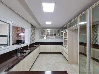 Interior de uma cozinha com armários em madeira e piso de cerâmica.
