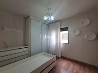 Quarto interno com piso de madeira e armário embutido.