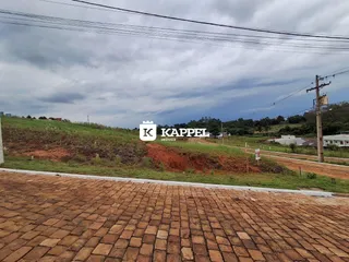 Vista externa de uma área com terra e vegetação ao fundo.