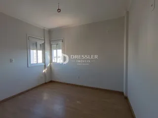 Foto de um ambiente interno com piso de madeira clara e paredes brancas.