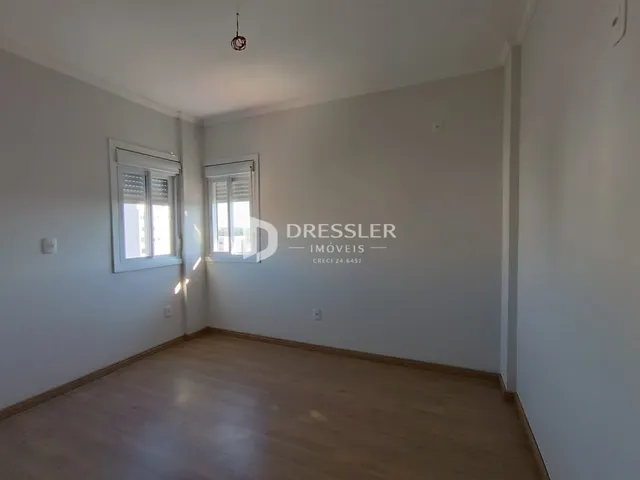Foto de um ambiente interno com piso de madeira clara e paredes brancas.