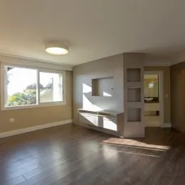 Sala de estar com grande janela e piso de madeira escura.