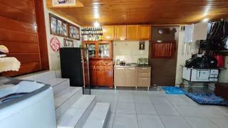 Sala de estar com painéis de madeira e área de cozinha em imóvel no Lajeado.