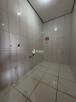 A foto mostra o interior de um banheiro com revestimento cerâmico branco.