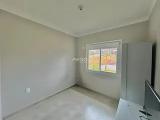 Ambiente interno de uma sala vazia com paredes brancas e piso claro.