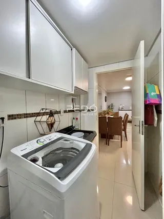 Interior de uma cozinha com armários brancos e revestimento cerâmico.
