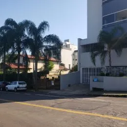 Fachada de um edifício residencial em Lajeado, Brasil, com vegetação ao redor.