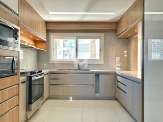 Interior de uma cozinha moderna com armários de madeira e bancadas claras.