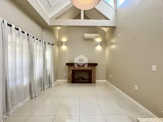 Sala de estar com lareira e janelas cobertas por cortinas brancas.