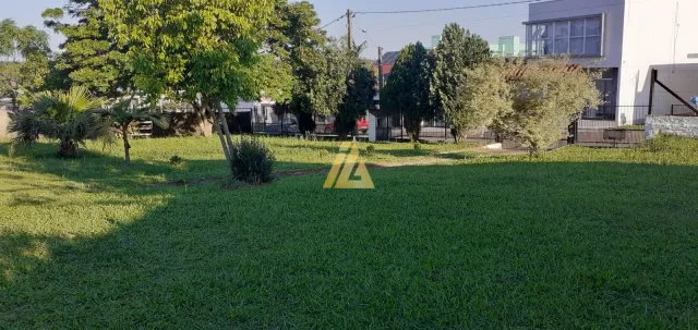 Vista externa de um gramado verde com árvores e cerca em uma propriedade.