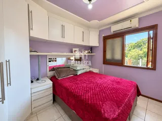 Quarto com cama e armários brancos em uma sala de Lajeado.
