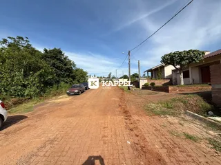 Vista externa de uma propriedade com estrada de terra vermelha.
