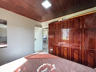 Interior de um quarto com paredes brancas e teto de madeira escura.