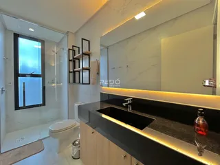 Banheiro moderno com box de vidro e bancada escura.