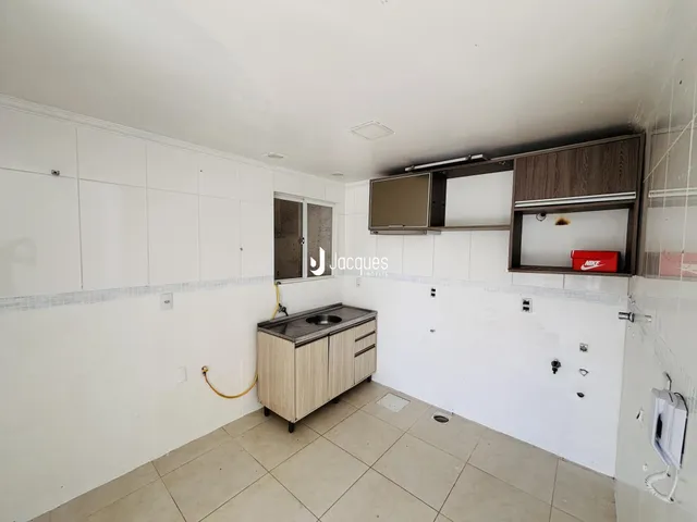 Cozinha com armários e piso de cerâmica branca.