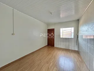 Interior de um ambiente com piso de madeira e paredes brancas.