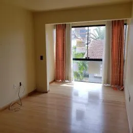 Vista interna de um ambiente com piso de madeira e abertura para o exterior.