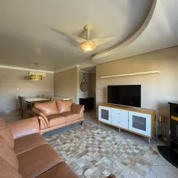 Foto de uma sala de estar com sofá e televisão na parede.