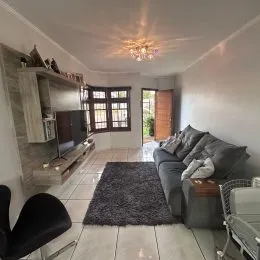 Foto interna de uma sala de estar com sofá e estantes de madeira.