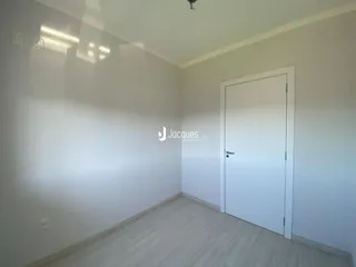 Parede interna de um cômodo com piso de madeira clara e porta branca.