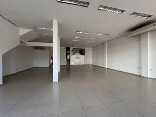 Vista interna de um espaço amplo com paredes brancas e piso de cerâmica.