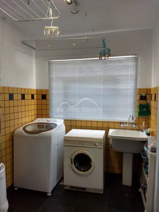 Ambiente interno mostrando máquinas de lavar e revestimento de azulejos amarelos.