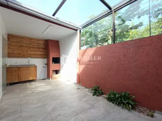 Interior de uma sala com piso de cerâmica e parede de tijolo aparente.