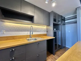 Cozinha moderna com armários cinzas e bancada de madeira.