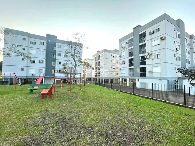 Vista externa de um complexo de apartamentos em Lajeado, Brasil, com área verde e playground.