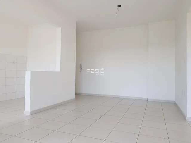 Ambiente interno de uma sala com piso de cerâmica e paredes brancas.