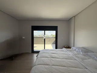 A foto mostra um quarto com piso de madeira clara e uma grande cama de casal.