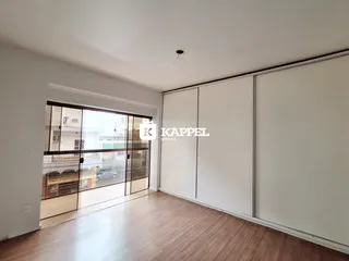 Sala de estar com piso de madeira e porta de vidro que dá acesso ao exterior.