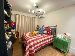 Quarto com cama coberta por uma colcha vermelha e branca e ar-condicionado instalado.