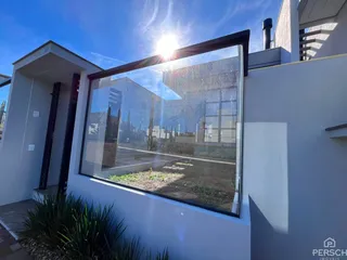 Foto da fachada de uma residência com uma grande janela refletindo o sol.
