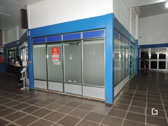 Fachada de um imóvel comercial com grandes janelas de vidro e estrutura azul.