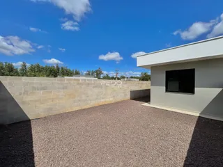 Fachada de uma residência com muro de alvenaria e entrada de cascalho.