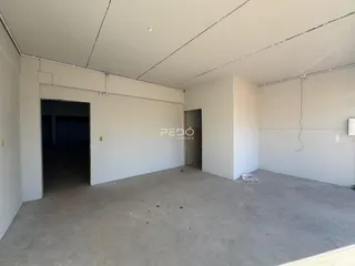Interior de um espaço vazio com paredes brancas e piso de concreto.