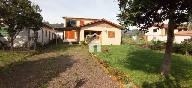Fachada de uma casa em Lajeado, Brasil, com jardim gramado e vegetação.