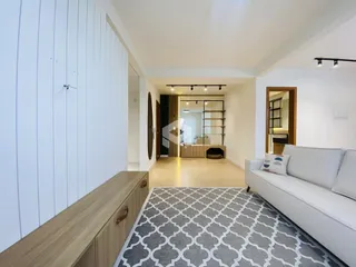 Sala de estar com piso de madeira clara e sofá branco.