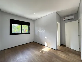Sala de estar com piso de madeira e janela com vista para a vegetação.