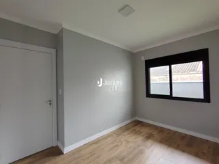 Foto de um corredor interno com paredes claras e piso de madeira.