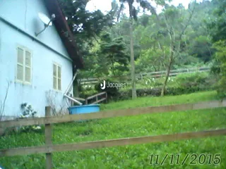 Fachada de uma casa branca com cerca de madeira e grama verde