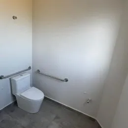 Foto de um banheiro interno mostrando um vaso sanitário e um corrimão de apoio.
